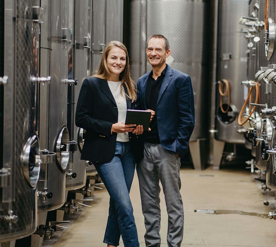 2 people in the wine cellar with steel tanks