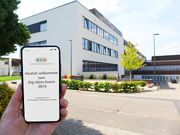 Handy Screen mit der Aufschrift: "Herzlich Willkommen zum Digi- Weinforum 2019" vor dem Gebäude des Weincampus Neustadt