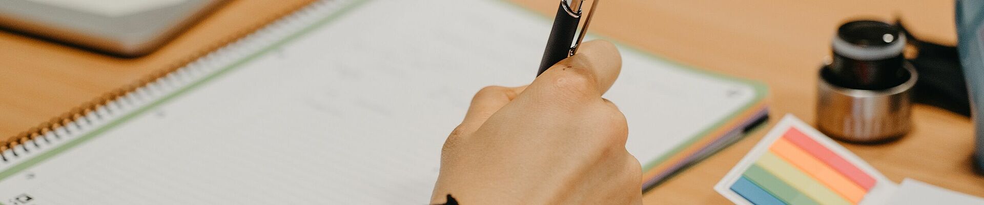 Close-up of hand holding pen and writing pad