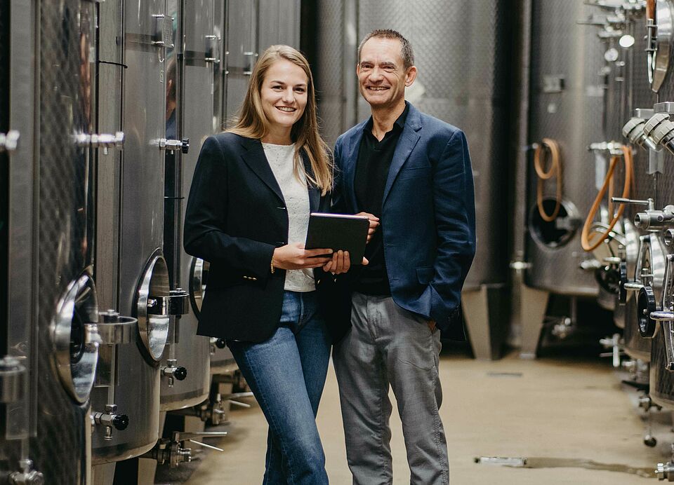 2 people in the wine cellar with steel tanks