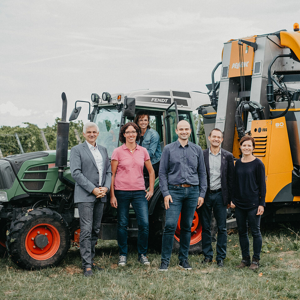 Forschungsteam steht vor Traktor mit modernem Anbaugerät