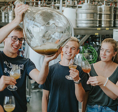 Studierende begutachten einen Glasballon mit Most im Technikum