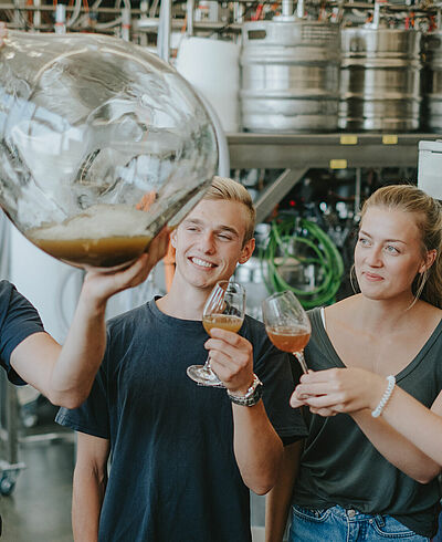 Students inspect a glass carboy with cider in the technical center