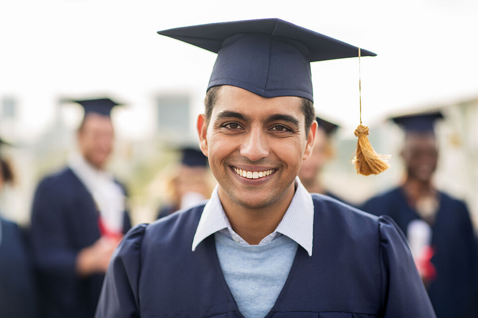 lächelnder Student mit Absolventenhut 