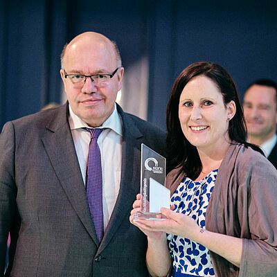 Federal Minister of Economics Peter Altmeier stands next to a woman holding a Fair'n Green trophy