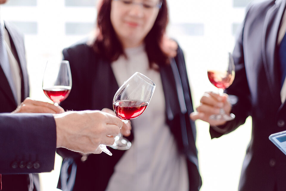 Mehrere Personen beim Verkosten von Rotwein