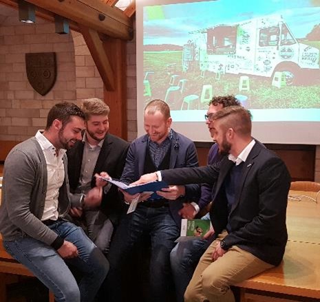 Five young gentlemen sit around a book and talk